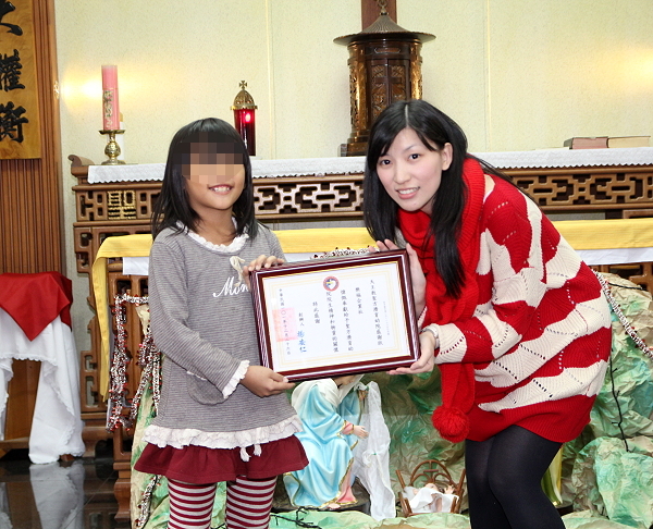 圣方济育幼院的小朋友（左）代表致赠感谢状予乐福企业社 - 