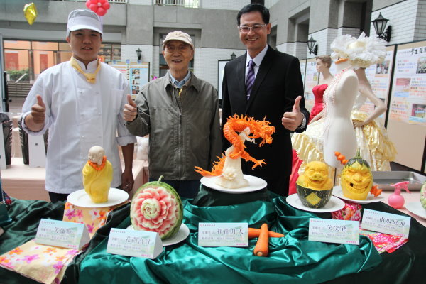  王創辦人(圖中)、陳建勝校長(圖右)對周加和同學(左一)的果雕作品稱讚不已 - 