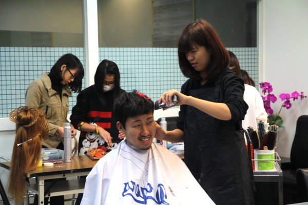美髮沙龍店長黃鈺茹(右)正在為西原良治同學(左)理髮 - 